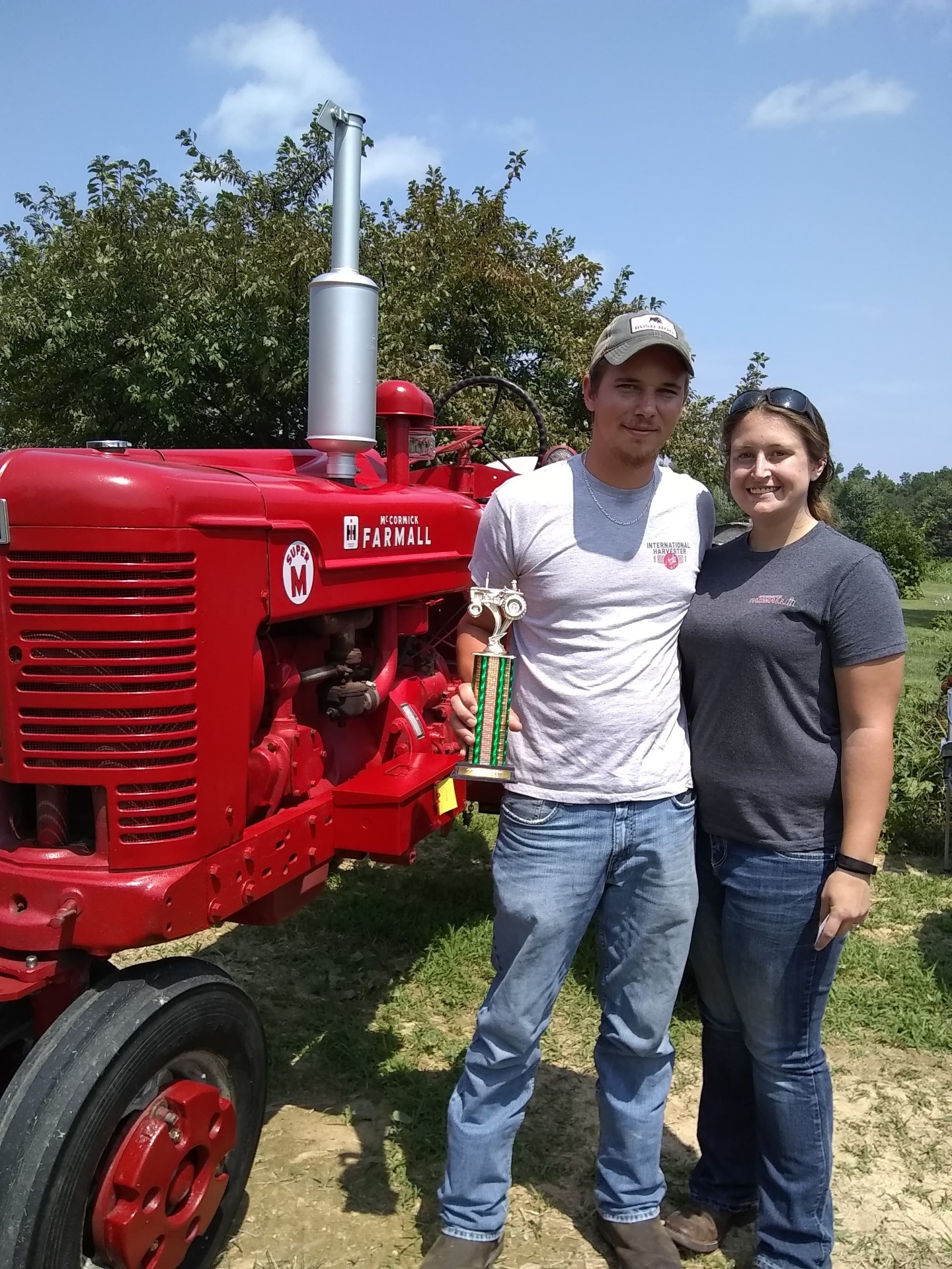 Jeremiah Wheeler standing beside a restored red Farmall tractor