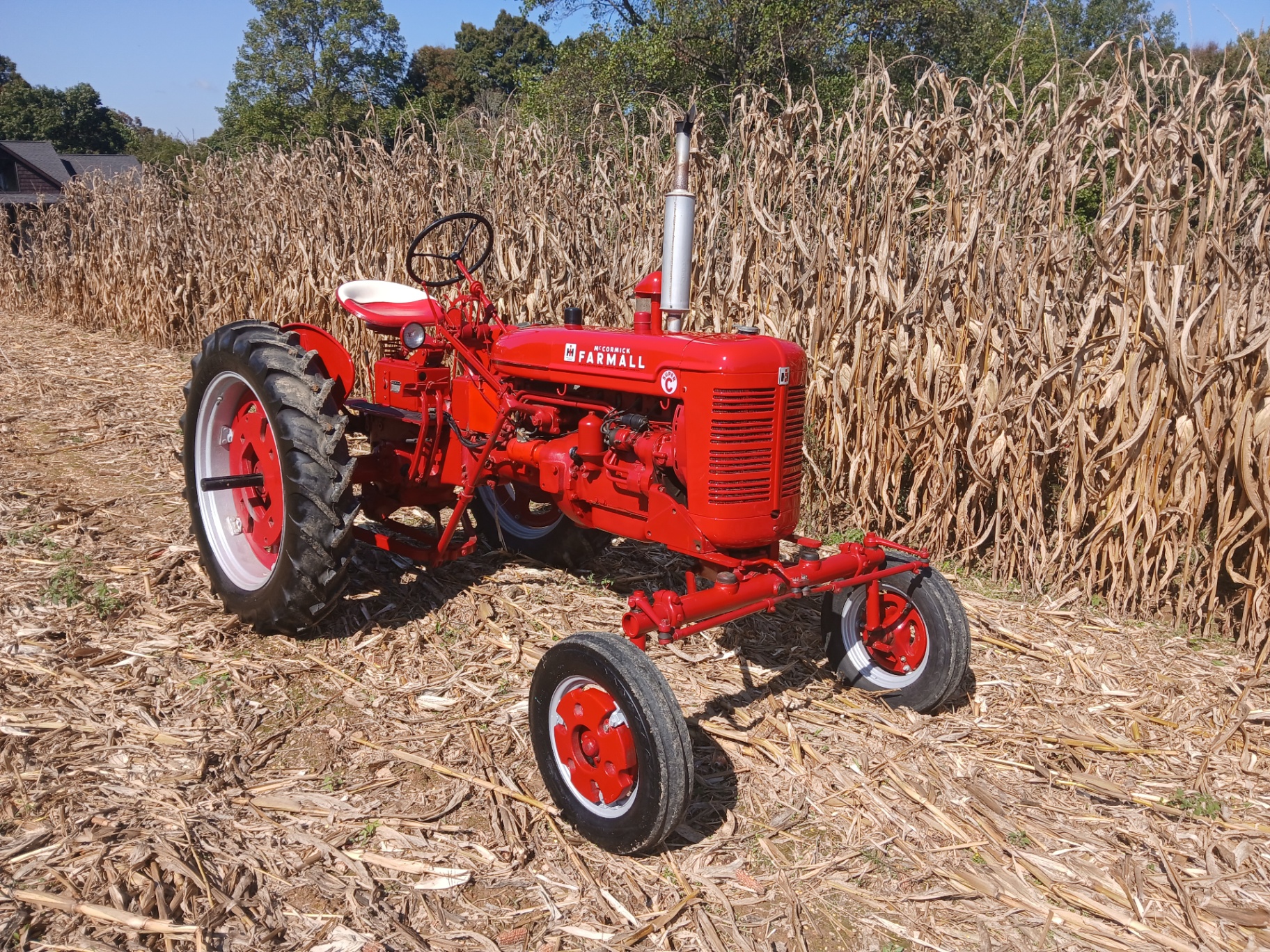 Restored red McCormick Farmall Super C tractor standing in a cornfield